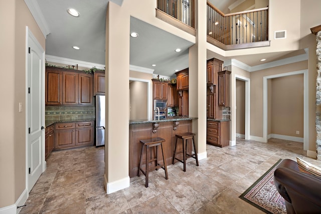 kitchen featuring stainless steel appliances, a kitchen breakfast bar, ornamental molding, decorative backsplash, and recessed lighting