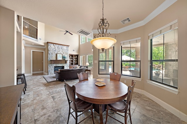 dining area featuring ornamental molding, baseboards, a stone fireplace, and a high ceiling