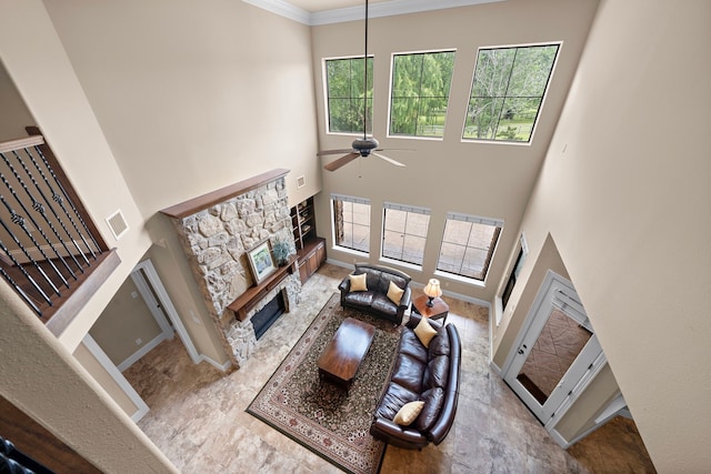 living room with a fireplace, a high ceiling, plenty of natural light, a ceiling fan, and baseboards