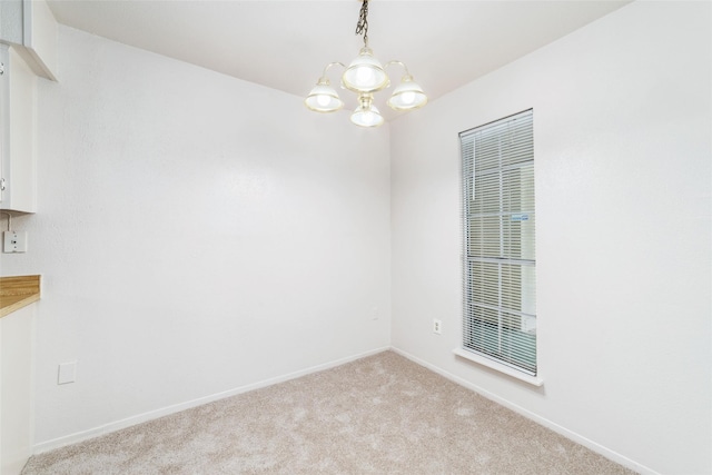 carpeted spare room with baseboards and a notable chandelier