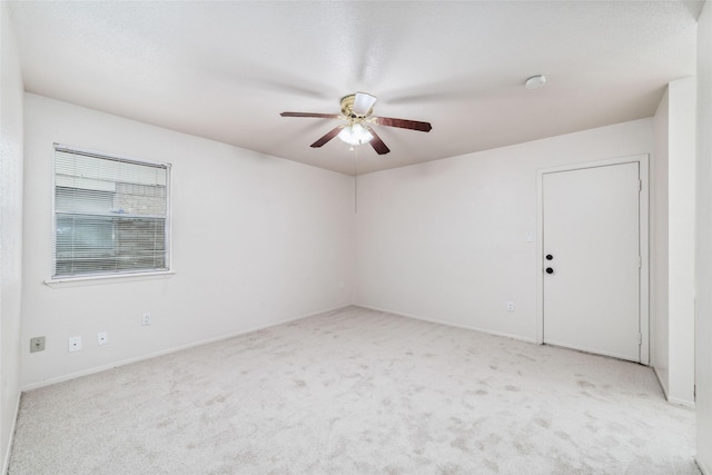 empty room featuring light colored carpet, baseboards, and ceiling fan