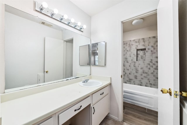 full bathroom with shower / bath combination, visible vents, wood finished floors, and vanity