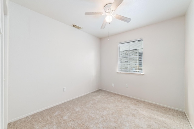 carpeted empty room featuring ceiling fan, visible vents, and baseboards