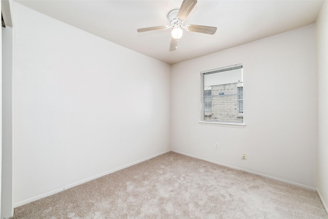 carpeted spare room featuring baseboards and ceiling fan