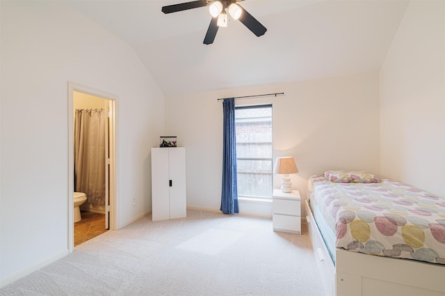 bedroom with lofted ceiling, baseboards, light colored carpet, a ceiling fan, and ensuite bath