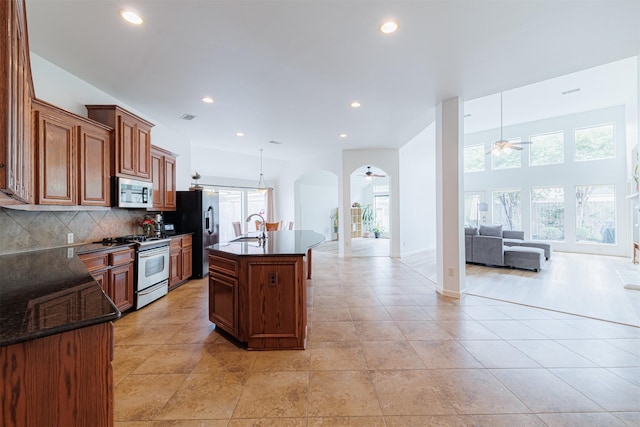 kitchen with open floor plan, ceiling fan, arched walkways, a sink, and appliances with stainless steel finishes