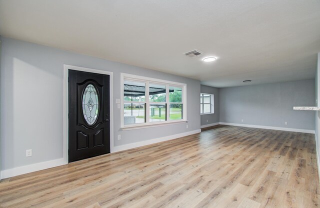 foyer entrance with baseboards, wood finished floors, and visible vents
