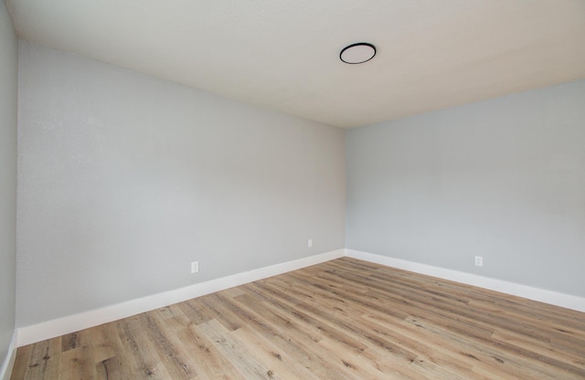 spare room with baseboards and wood finished floors