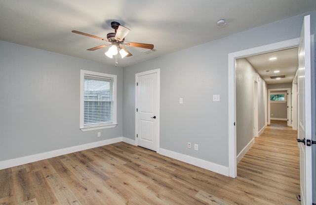 unfurnished room featuring baseboards, light wood-type flooring, plenty of natural light, and ceiling fan