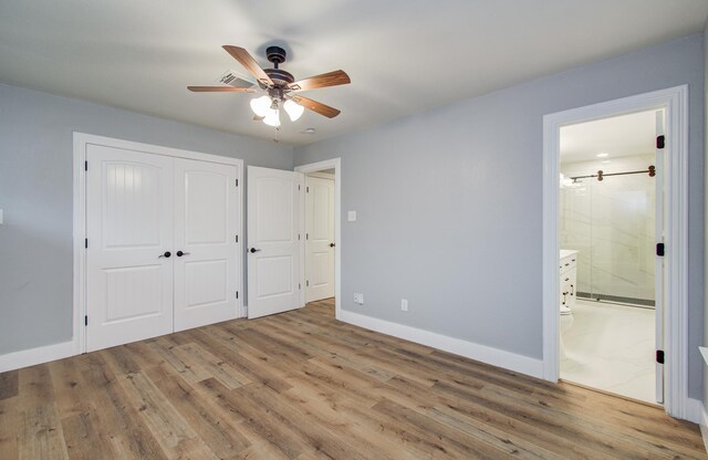 unfurnished bedroom featuring a closet, baseboards, ensuite bath, and wood finished floors