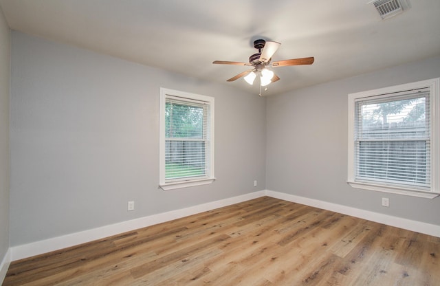 unfurnished room with baseboards, visible vents, ceiling fan, and wood finished floors