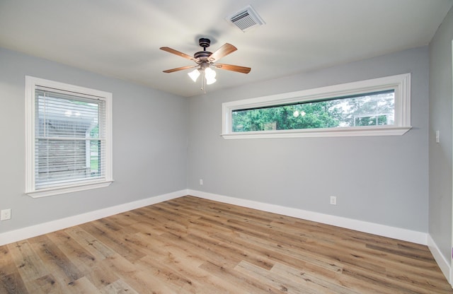 empty room featuring baseboards, a ceiling fan, wood finished floors, and visible vents