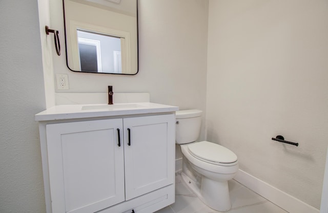 half bathroom with vanity, baseboards, tile patterned flooring, and toilet