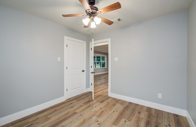 spare room with baseboards, a ceiling fan, visible vents, and light wood-type flooring