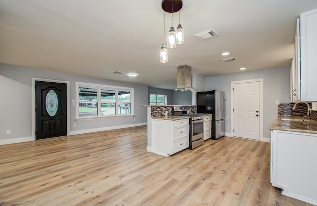 kitchen with exhaust hood, visible vents, appliances with stainless steel finishes, a sink, and white cabinets