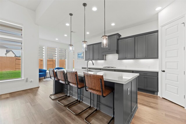 2122 Rosybill Dr, Katy, TX 77494 - kitchen featuring gas cooktop, decorative backsplash, a sink, light countertops, and light wood-style floors