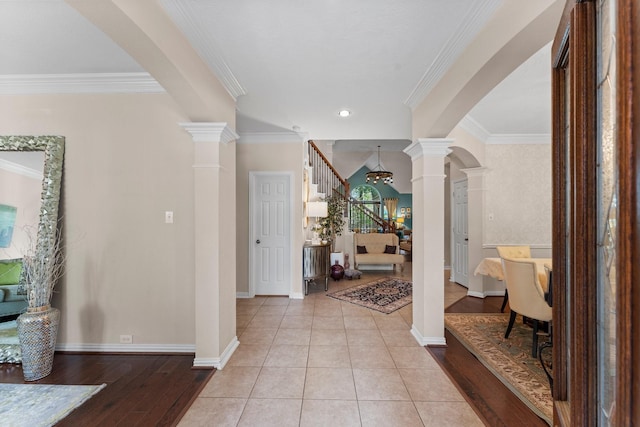 entryway with arched walkways, ornamental molding, decorative columns, and stairs