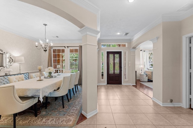 entryway featuring crown molding, arched walkways, decorative columns, and a notable chandelier
