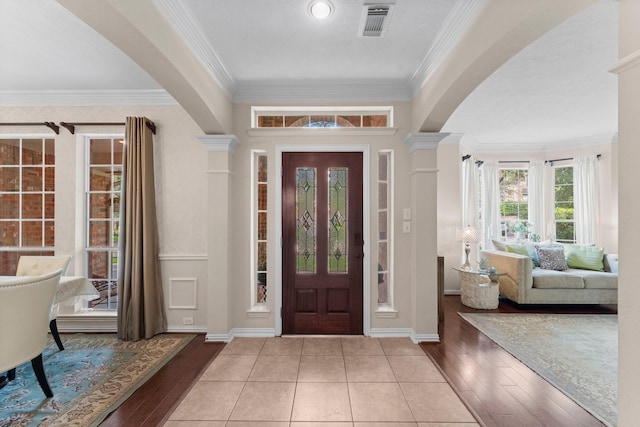 entrance foyer with arched walkways, ornamental molding, ornate columns, and wood finished floors