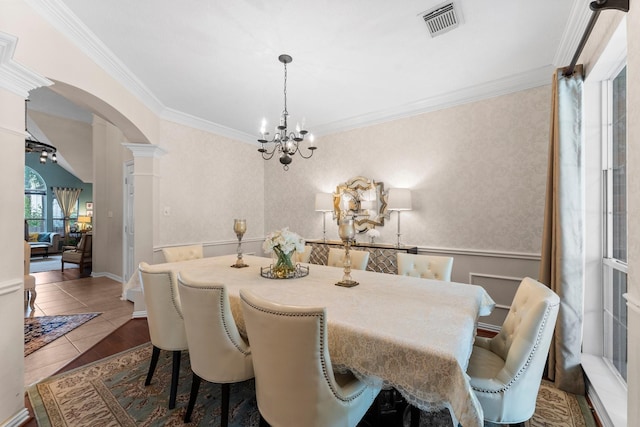 dining area with decorative columns, visible vents, arched walkways, a notable chandelier, and ornamental molding