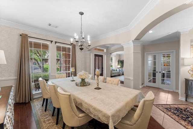 dining area featuring crown molding, arched walkways, a chandelier, french doors, and visible vents