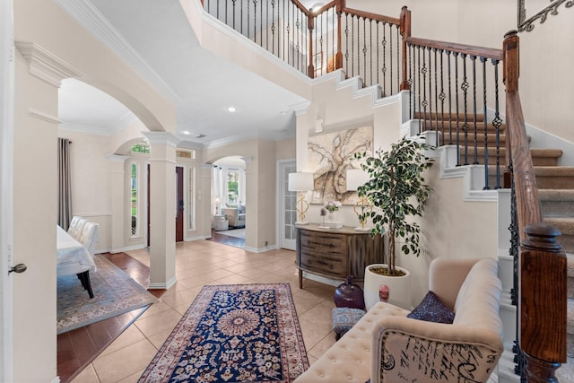 entrance foyer with tile patterned flooring, arched walkways, decorative columns, and ornamental molding