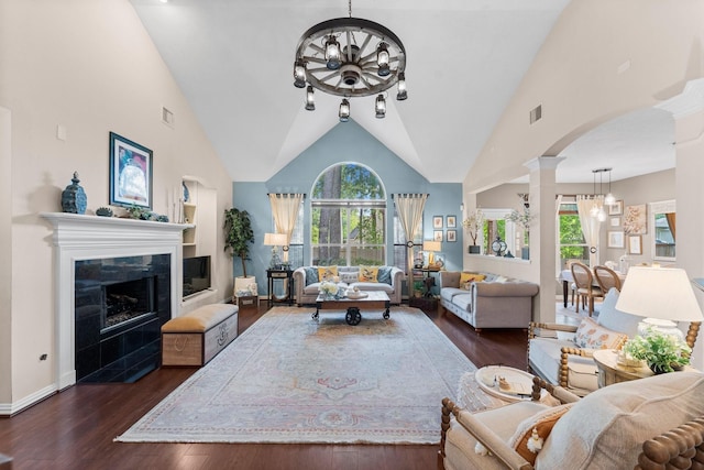 living room with decorative columns, a notable chandelier, plenty of natural light, and dark wood finished floors