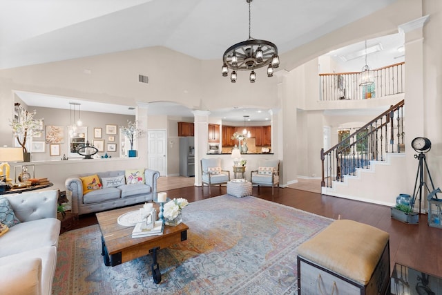 living room with an inviting chandelier, arched walkways, high vaulted ceiling, decorative columns, and wood finished floors