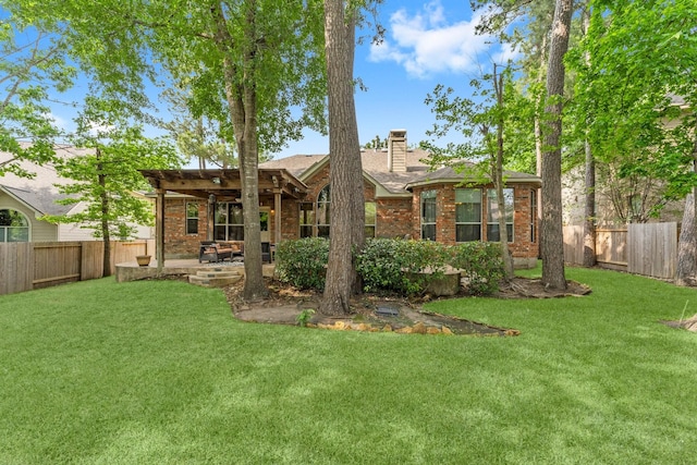 rear view of property with a yard, brick siding, a chimney, and a fenced backyard