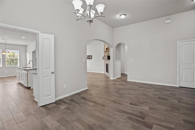 spare room featuring arched walkways, baseboards, a chandelier, and a sink