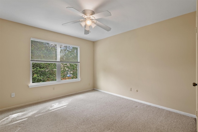 carpeted spare room featuring baseboards and ceiling fan
