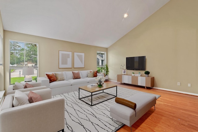 living room with baseboards, wood finished floors, and high vaulted ceiling