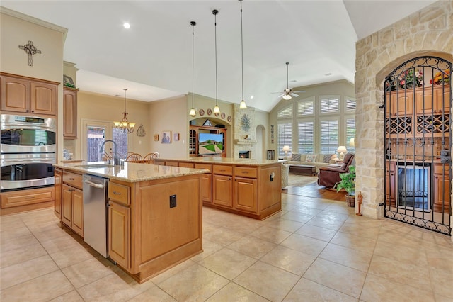 kitchen featuring a sink, an island with sink, a healthy amount of sunlight, and a large fireplace