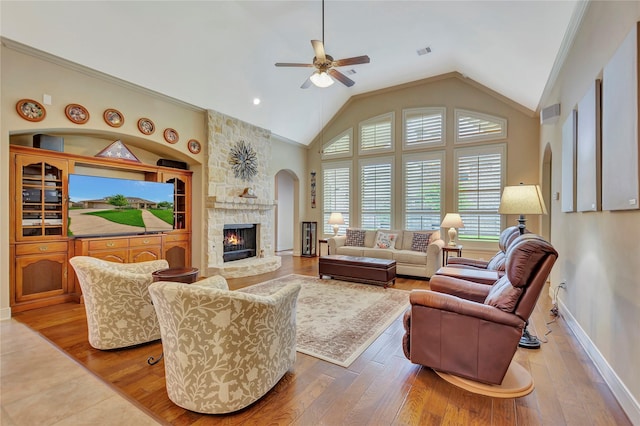 living area featuring ceiling fan, a fireplace, vaulted ceiling, hardwood / wood-style flooring, and baseboards