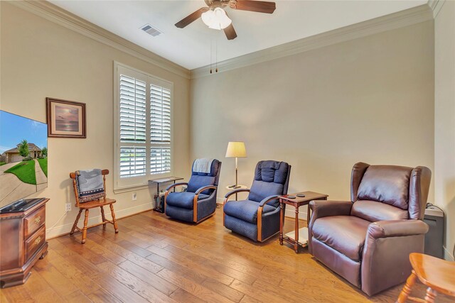 living area featuring a ceiling fan, visible vents, ornamental molding, and light wood-style floors