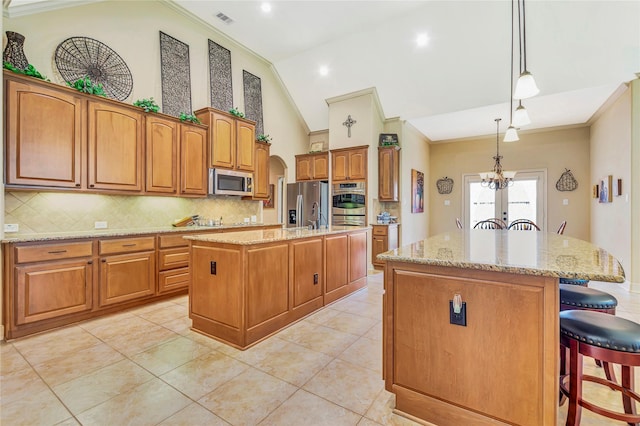 kitchen with a center island, stainless steel appliances, backsplash, visible vents, and ornamental molding