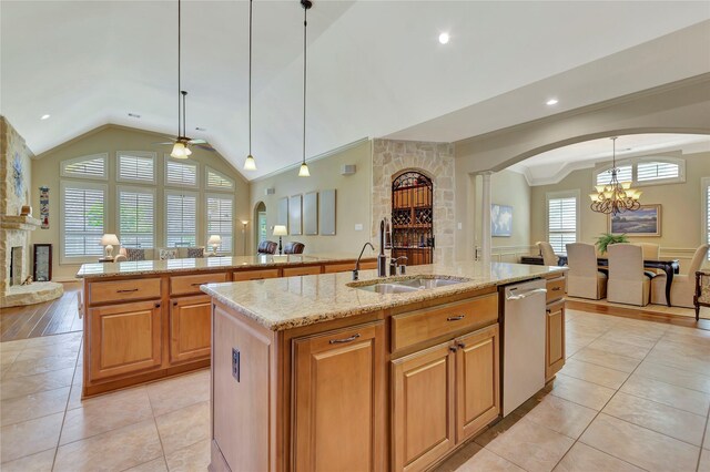 kitchen featuring a sink, arched walkways, an island with sink, ceiling fan with notable chandelier, and open floor plan