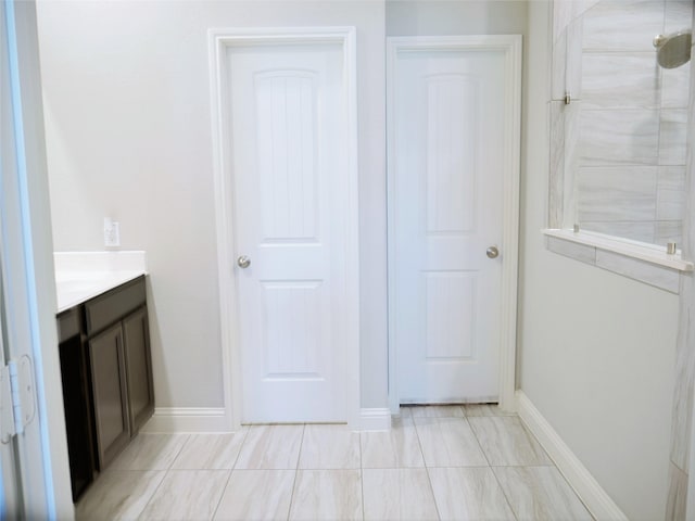 full bathroom featuring vanity, baseboards, and tiled shower