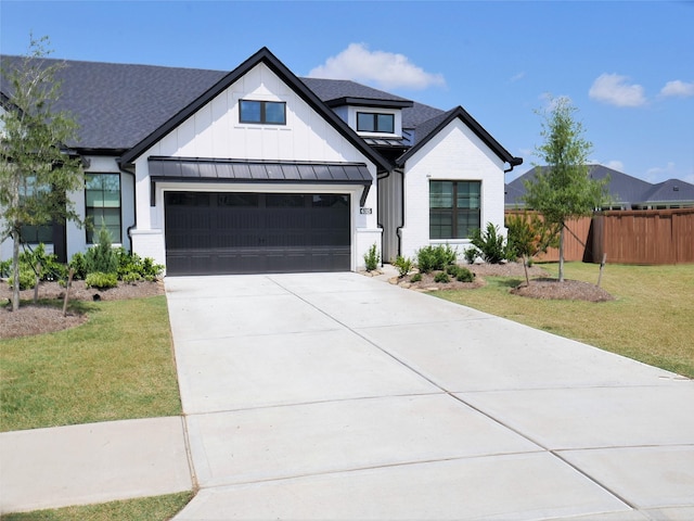 modern inspired farmhouse featuring board and batten siding, a standing seam roof, driveway, fence, and a front lawn