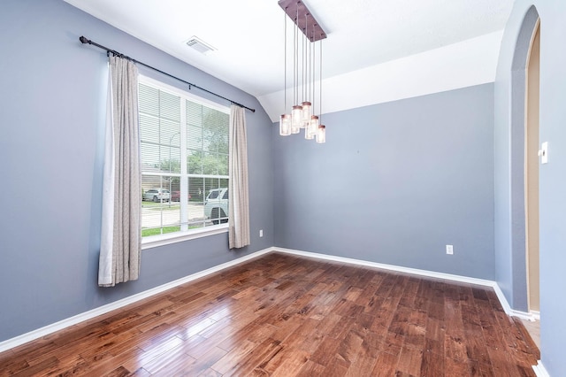 empty room featuring dark wood-type flooring, arched walkways, a chandelier, baseboards, and vaulted ceiling