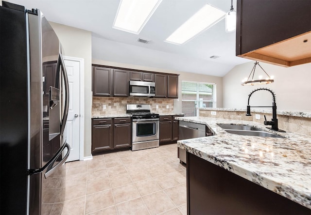 kitchen featuring appliances with stainless steel finishes, a sink, tasteful backsplash, light tile patterned flooring, and dark brown cabinetry