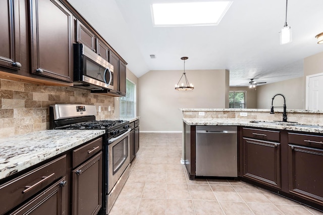 kitchen featuring appliances with stainless steel finishes, a sink, backsplash, dark brown cabinetry, and lofted ceiling