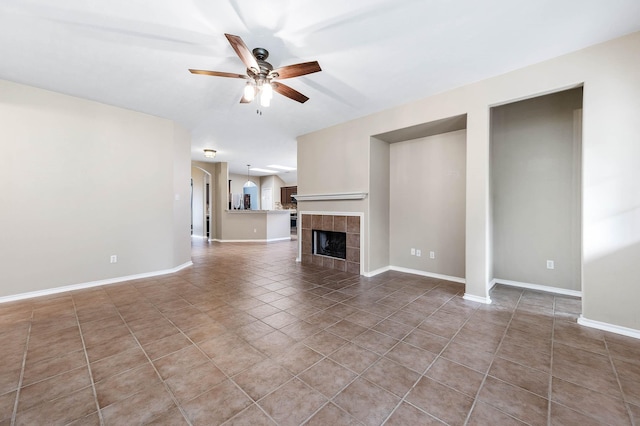 unfurnished living room with a ceiling fan, tile patterned flooring, a fireplace, and baseboards