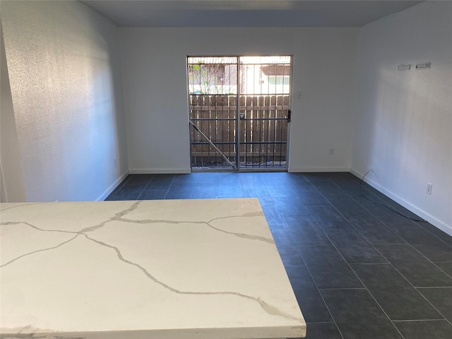 tiled empty room featuring baseboards