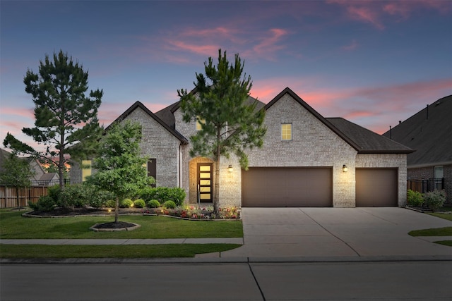 view of front facade with fence, an attached garage, driveway, and brick siding