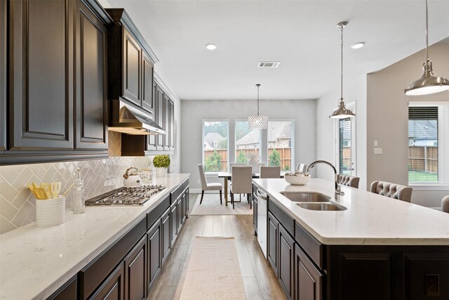 kitchen featuring backsplash, visible vents, appliances with stainless steel finishes, a sink, and under cabinet range hood