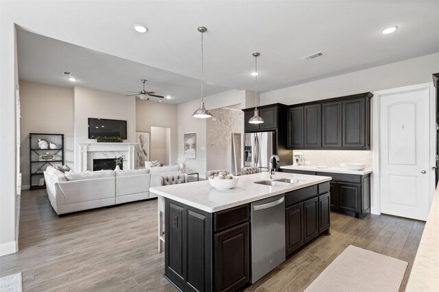 kitchen featuring a ceiling fan, visible vents, a center island with sink, a sink, and stainless steel appliances