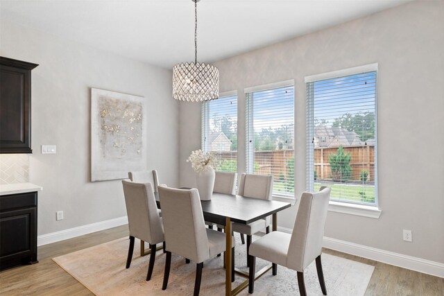 dining area featuring baseboards, an inviting chandelier, and light wood-style floors