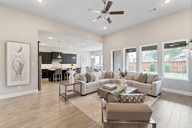 living room featuring light wood finished floors, a ceiling fan, baseboards, recessed lighting, and visible vents