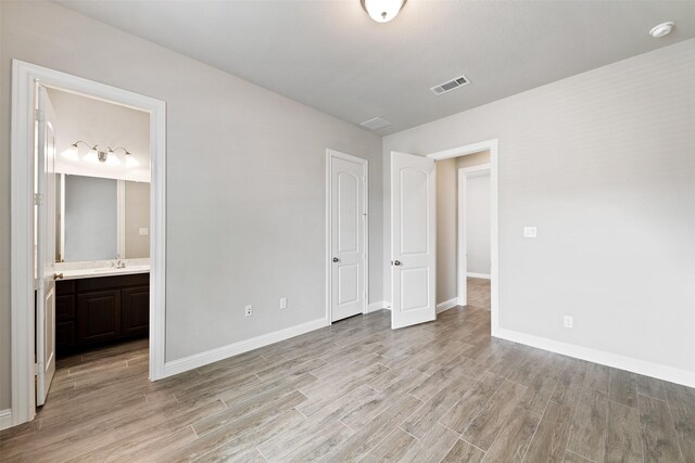 unfurnished bedroom featuring baseboards, light wood-style flooring, and visible vents